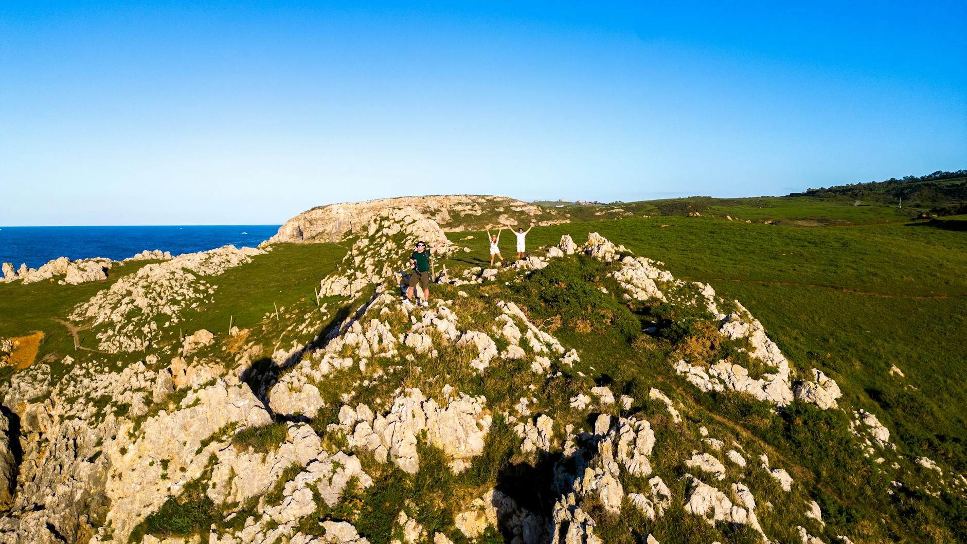 A stunning aerial view of the rocky cliffs and coastline in Asturias, Spain, with hikers enjoying the scenery.