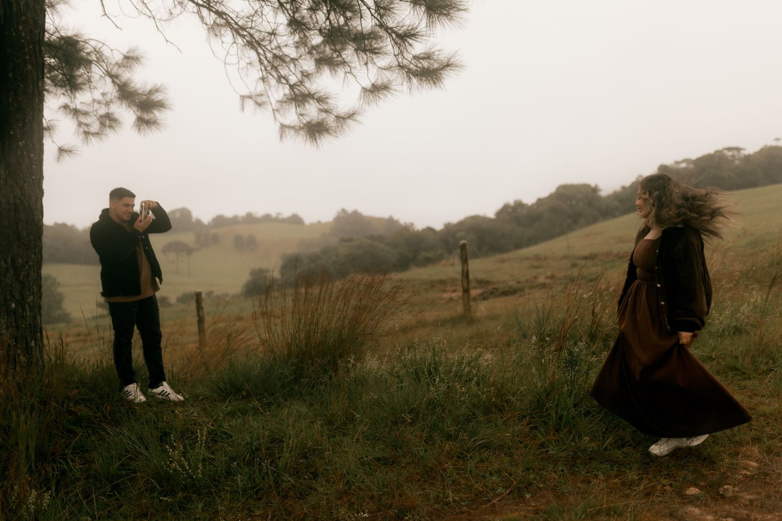 Photographer taking a picture of a woman in a misty, serene countryside setting.