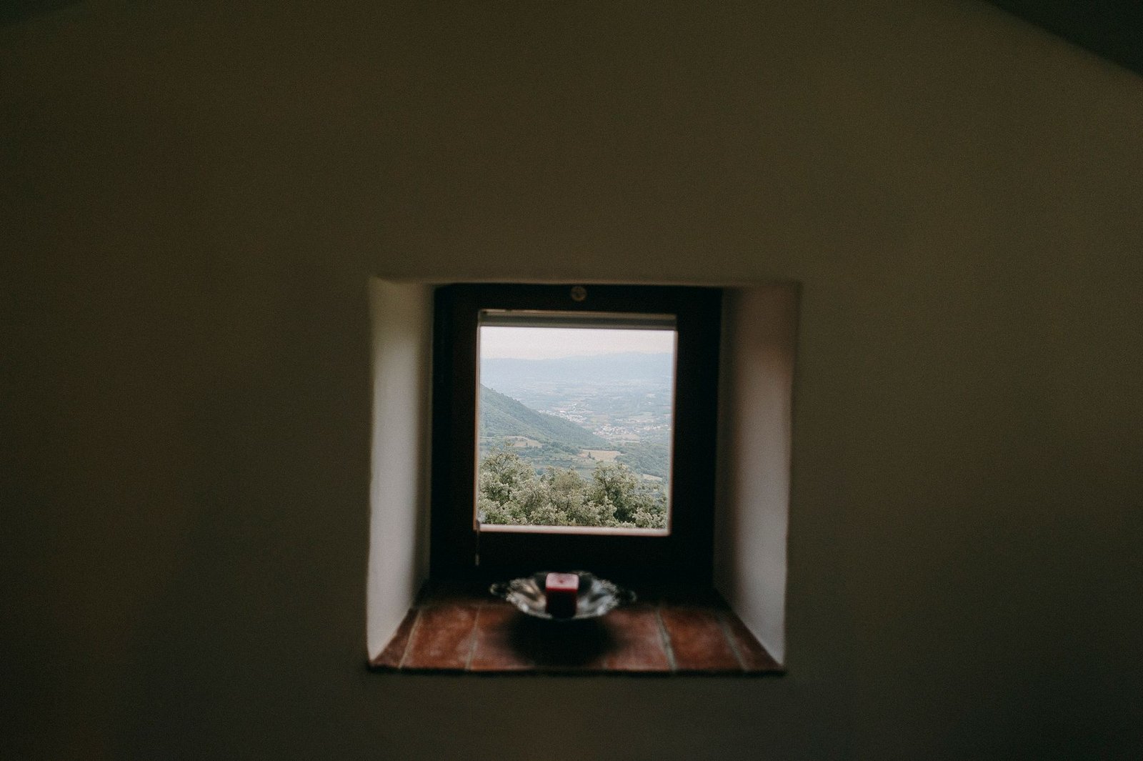 A serene view of distant mountains through a rustic window with candle accent.