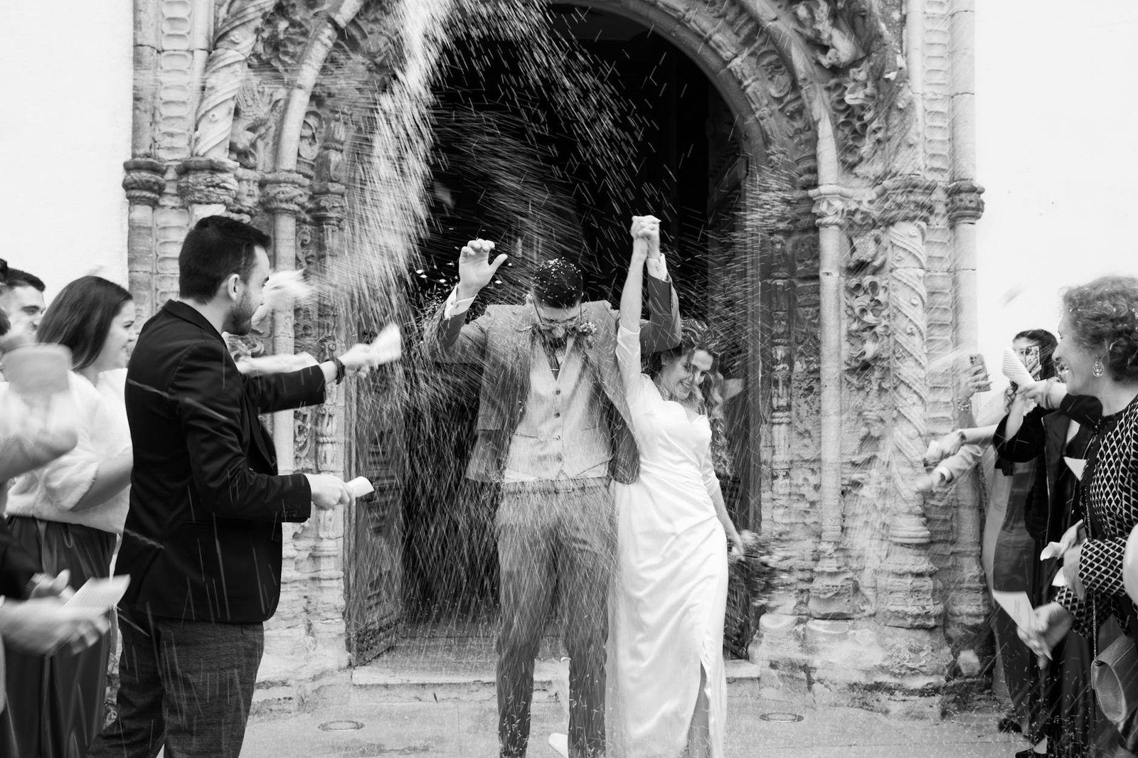 A joyful bride and groom celebrate with guests outside a historic church