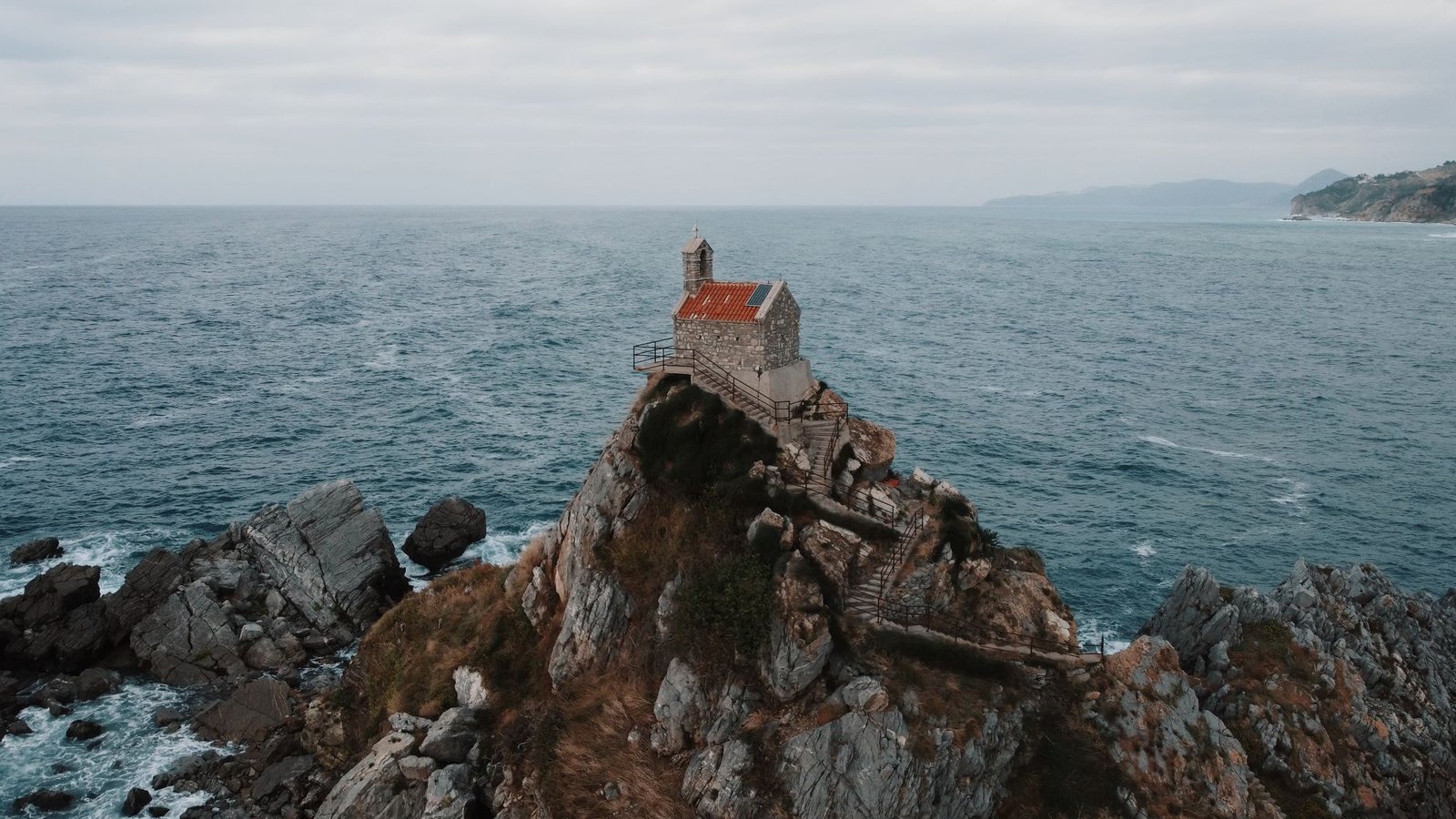 Stunning aerial view of a picturesque church on a rocky cliff in Petrovac, Montenegro.